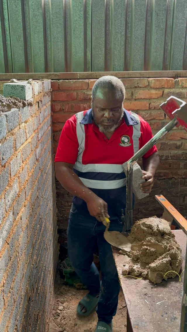 Participant using a hand tool beside mortar and a training wall