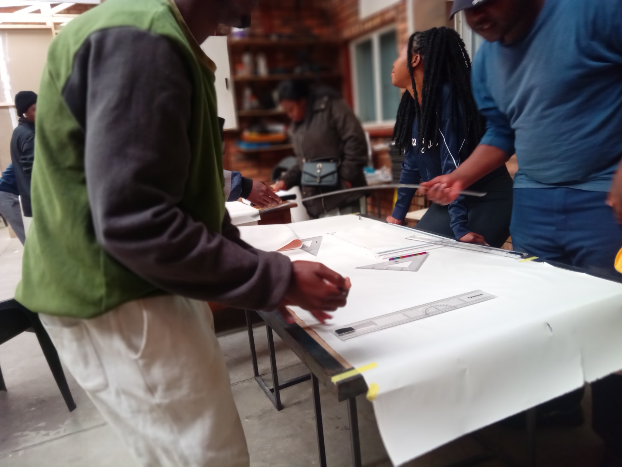AIET engineering drawing learners working with rulers and set squares on a drafting table