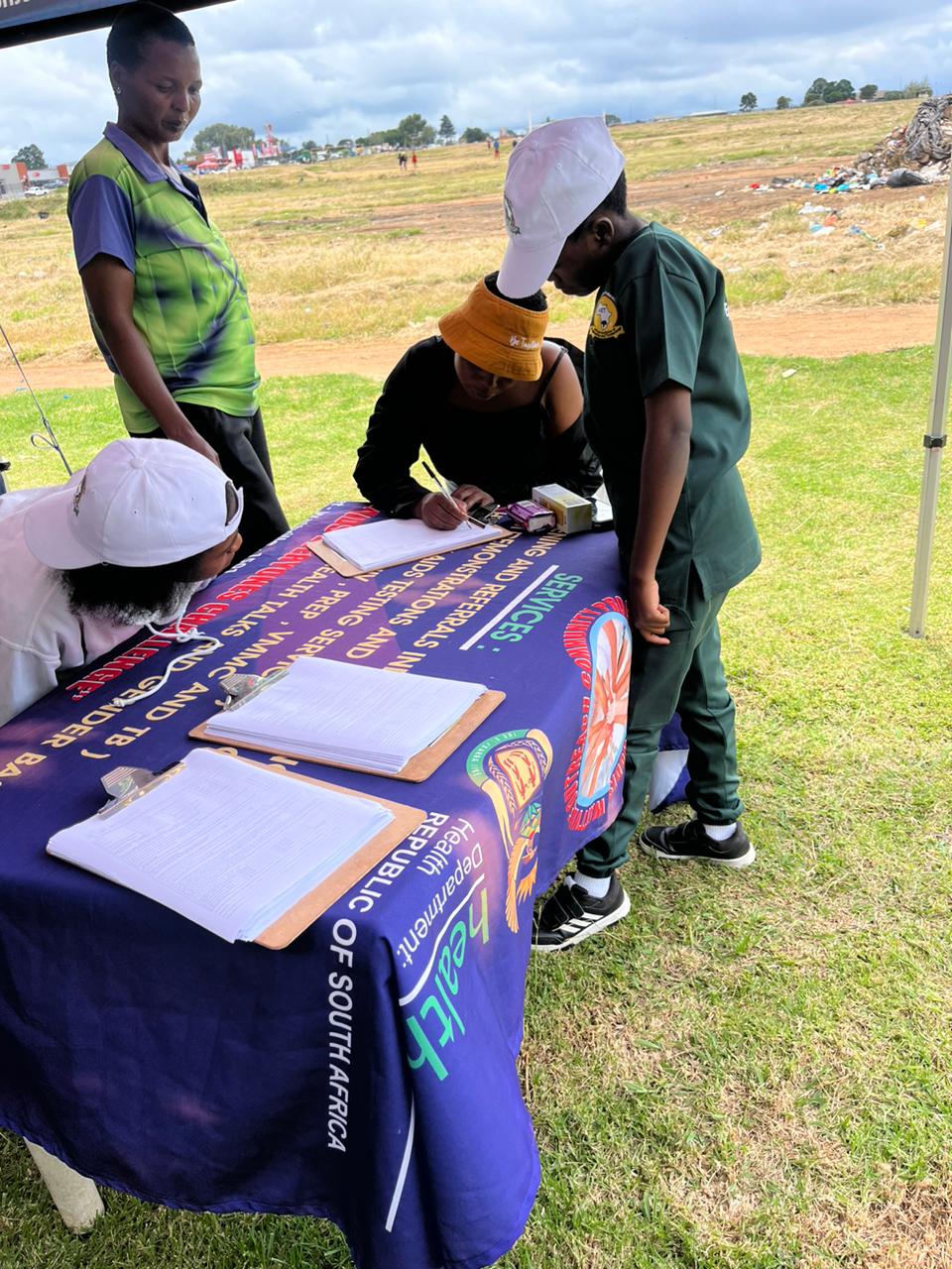 AIET HPO outreach desk with students completing registration forms for health services