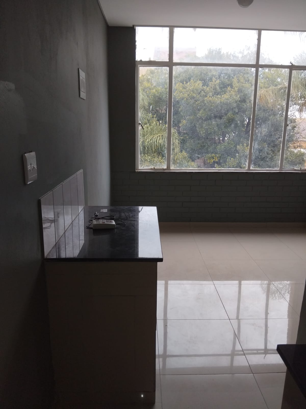 A clean AIET student accommodation studio space with tiled flooring and a kitchenette area