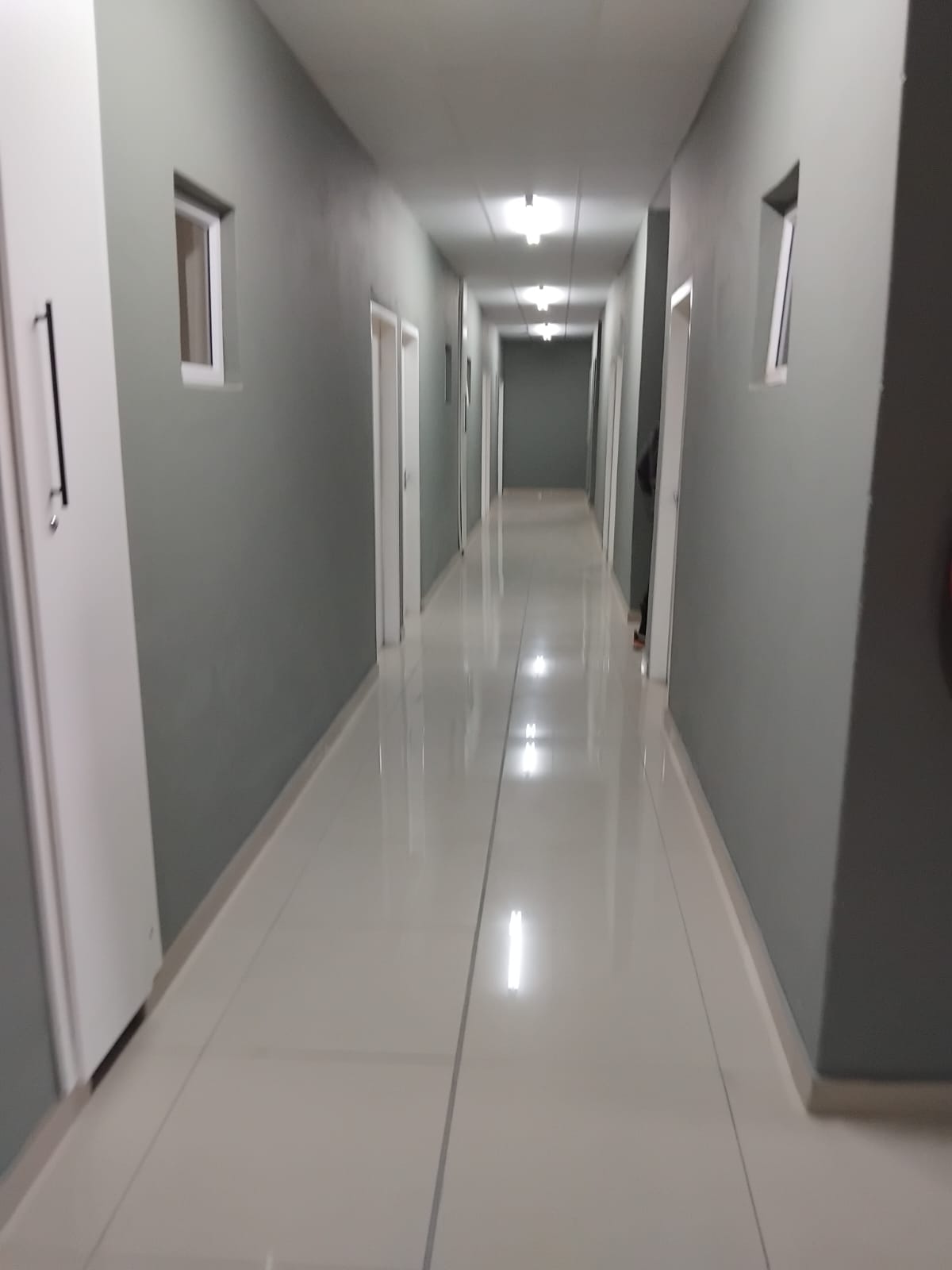 A clean, bright student residence corridor with multiple room doors and tiled flooring